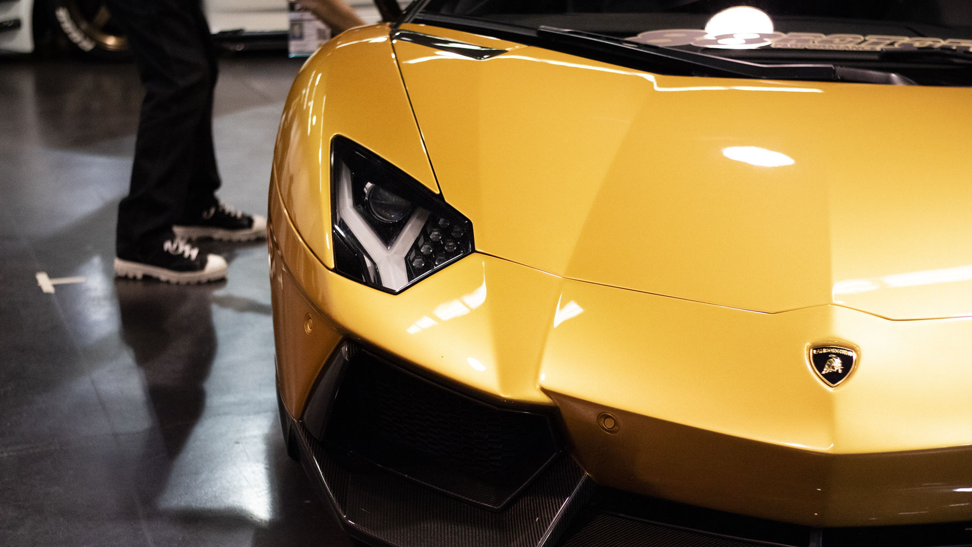 Photo of the front of a yellow/gold/orange colored Lamborghini at SPOCOM Anaheim 2019.